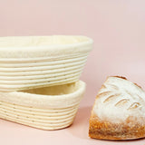 Two woven bread baskets and a loaf of bread on a pink background